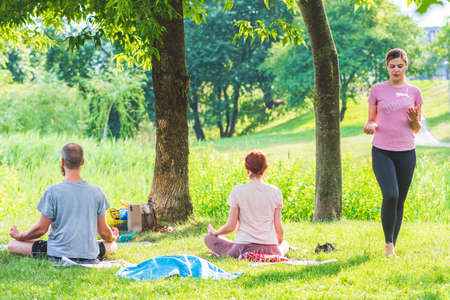 Vilnius, Lithuania - July 1 2021: Outdoor or outside yoga class or lesson on the grass in the park with beautiful teacher or instructor on sunsetのeditorial素材