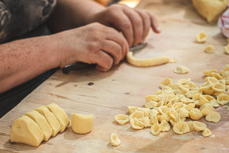 Local woman preparing in the street of Bari old town orecchiette orecchietta, made with durum wheat and water, handmade pasta typical of Puglia or Apulia, a region of Southern Italy, close upの写真素材