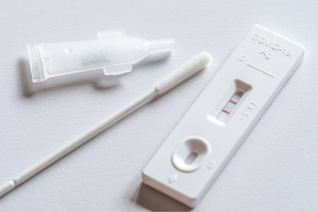 Positive Covid-19 antigen test kit, one step coronavirus antigen rapid test, saliva swab, on a white table, close upの写真素材