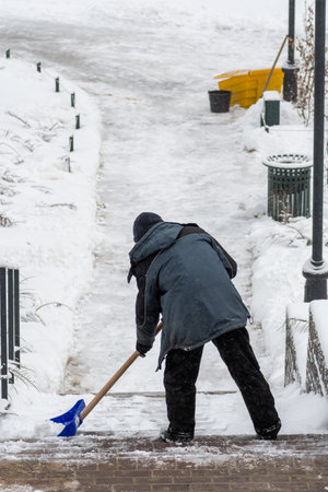 Man shovels snow on a stairway after a big snow storm, verticalの写真素材