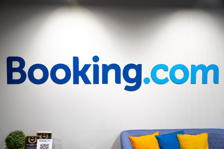 Vilnius, Lithuania - February 13 2022: Booking.com logo on a white wall of an office lighted by artificial lights like on a theater stage, travel and hotel concept industryのeditorial素材