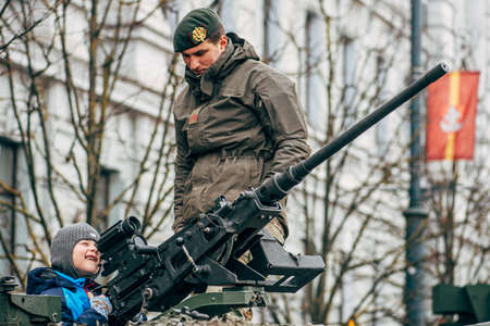 Vilnius, Lithuania - February 16 2022: Kid or child smiling and playing on the top of a tank or...
