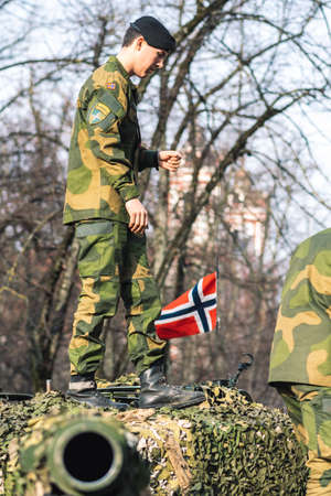 Vilnius, Lithuania - February 16 2022: Norwegian Army armored tank with cannon and camouflage coating with soldier on it and flag of Norway, verticalのeditorial素材