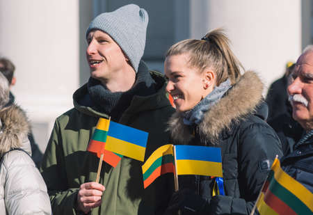 Vilnius, Lithuania - March 11, 2022: Peaceful demonstration against war, Putin and Russia in support of Ukraine, with a couple of friends with Ukrainian and Lithuanian flags togetherのeditorial素材