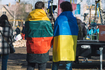 Vilnius, Lithuania - March 2, 2022: Peaceful demonstration against war, Putin and Russia in support of Ukraine, with people, placards and a couple with Ukrainian and Lithuanian flagsのeditorial素材