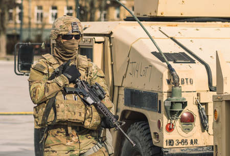 United States - March 29 2022: United States Marine Corps soldier with covered face and sunglasses, shotgun or rifle and armored vehicle humvee, USA or US army troops ready for drills or warのeditorial素材