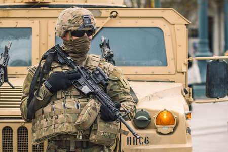 United States - March 29 2022: United States Marine Corps soldier with covered face and sunglasses, shotgun or rifle and military vehicles, USA or US army troops ready for drills, battle or warのeditorial素材