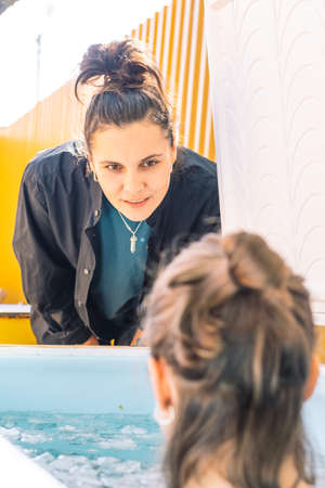 Vilnius, Lithuania - April 30 2022: Girl or woman bathing in the cold water among ice cubes with...