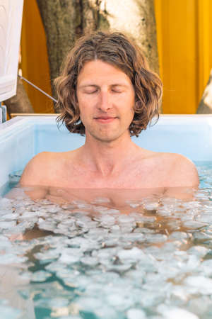 Vilnius, Lithuania - April 30 2022: Boy or man bathing in the cold water among ice cubes. Wim Hof Method, cold therapy, breathing techniques, yoga and meditationのeditorial素材