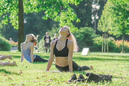 Vilnius, Lithuania - June 22 2022: Beautiful girls making outdoor or outside activity, yoga or gym on the grass in a public park in summerのeditorial素材