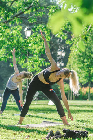 Vilnius, Lithuania - June 22 2022: Beautiful girls making outdoor or outside activity, yoga or gym on the grass in a public park in summerのeditorial素材