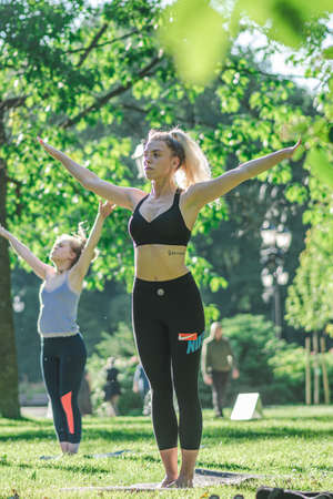 Vilnius, Lithuania - June 22 2022: Beautiful girls making outdoor or outside activity, yoga or gym on the grass in a public park in summerのeditorial素材