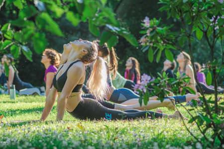 Vilnius, Lithuania - June 22 2022: Beautiful girls making outdoor or outside activity, yoga or gym on the grass in a public park in summerのeditorial素材