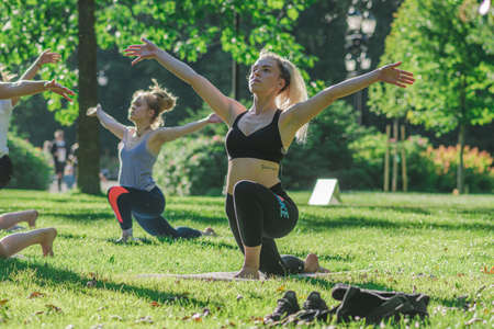 Vilnius, Lithuania - June 22 2022: Beautiful girls making outdoor or outside activity, yoga or gym on the grass in a public park in summerのeditorial素材