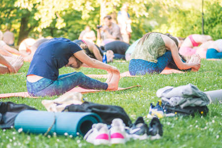 Vilnius, Lithuania - June 22 2022: Beautiful girls making outdoor or outside activity, yoga or gym on the grass in a public park in summerのeditorial素材