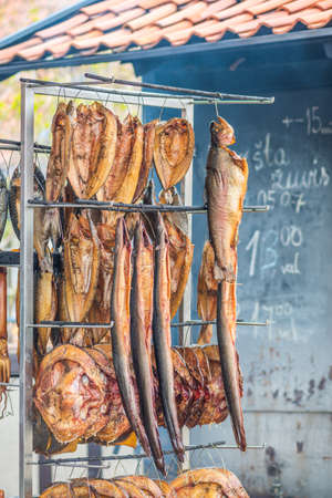 Hanging smoke-dried fish in a fish market just smoked with hardwood wood chips in a smoker and ready to eat, verticalの写真素材