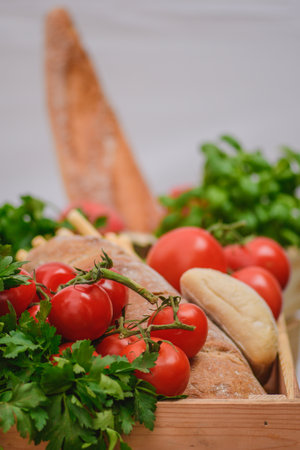 Fresh bio ripe red tomatoes with white bread, parsley leaves in a wooden box in a street food market, close upの写真素材