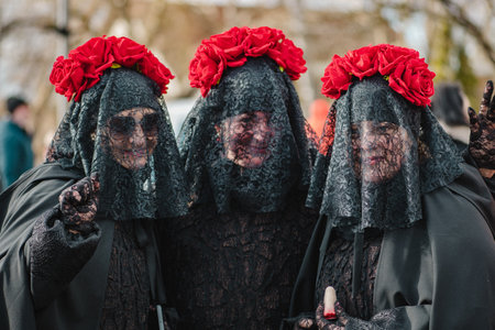 Trakai, Vilnius, Lithuania - February 19 2022: Three girls or women dressing in black with roses like widows during Uzgavenes, a Lithuanian folk festival during Carnival, seventh wのeditorial素材