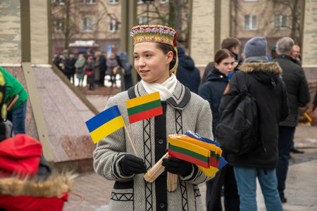 Vilnius Lithuania - March 11 2023: Pretty Lithuanian girl in traditional costume with Lithuanian and Ukrainian flags during a ceremonyのeditorial素材