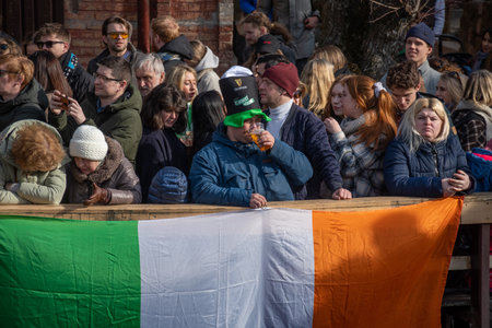 Vilnius, Lithuania - March 18 2023: Boy with big hat drinking beer during Irish St. Patrick's Day celebration along the banks of the Vilnele River in Uzupis, Vilnius, Lithuaniaのeditorial素材