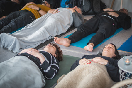 Vilnius, Lithuania - March 26 2023: Group of young people during a yoga class lying on a mat, breathing and meditating together with closed eyes, group activity, team building, semのeditorial素材