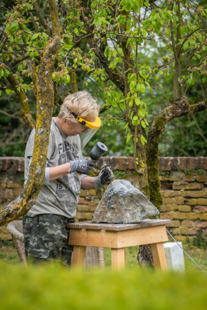 Sebastiano da Po, Italy - April 12 2023: Woman carving a stone during an outdoor sculpture lesson or class in the botanical garden of San Sebastiano da Po Castle near Torinoのeditorial素材
