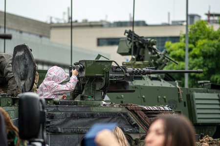Vilnius, Lithuania - June 17 2023: Kid or child playing with a machine gun on an armored military vehicle during a NATO festival before the summitのeditorial素材