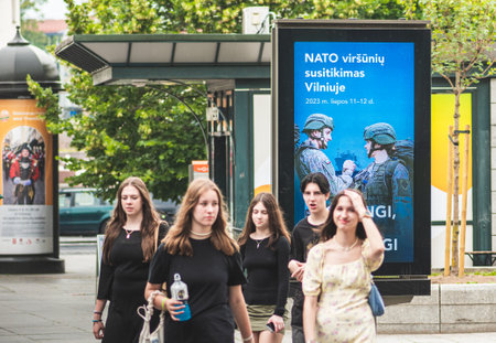 Vilnius, Lithuania - June 22 2023: Advertising banner informing about the upcoming Nato summit 2023 in the center of Vilnius, capital of Lithuania with teenagers walking nearbyのeditorial素材