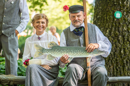 Riga, Latvia - July 10 2023: Beautiful smiling couple in traditional clothes and symbol of fish during XXVII Nationwide Latvian Song and XVII Dance Festivalのeditorial素材