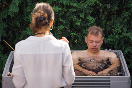 Man ice bathing in the cold water among ice cubes with instructor. Wim Hof Method, cold therapy, breathing techniques, yoga and meditationのeditorial素材