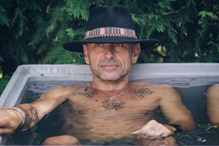 Boy or man smiling and ice bathing in the cold water among ice cubes. Wim Hof Method, cold therapy, breathing techniques, yoga and meditationのeditorial素材