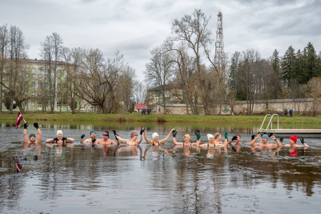 Preili, Latvia - November 18 2023: Girl ice bathing with gloves and hat in the cold water of a lake in Preili, Latvia. Wim Hof Method, cold therapy, breathing techniques, yoga andのeditorial素材