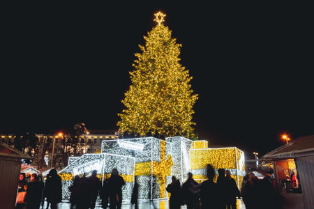 Vilnius, Lithuania - December 5 2023: Beautiful real Christmas tree with market, people and tourists...