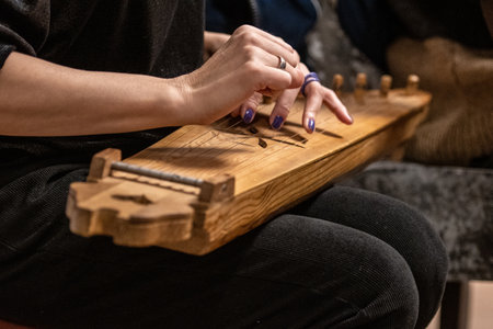 Fingers of a girl playing kankles, Lithuanian plucked string instrument belonging to the Baltic box...