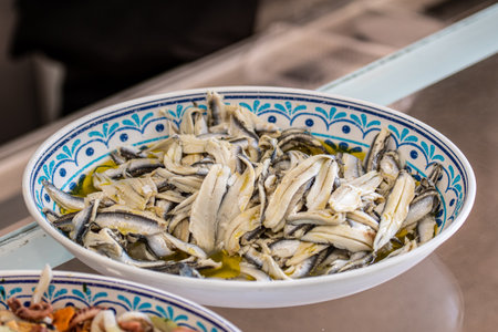 Marinated anchovies with vinegar, olive oil, pepper and parsley, in a decorated ceramic plate, close upの写真素材