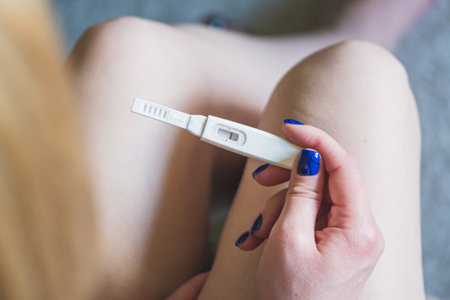 Young blonde girl sitting and looking at a negative pregnancy test, top viewの写真素材