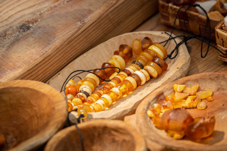 Variety of pieces of amber in a wooden pot. Amber of different colors and sizes in a craft marketの写真素材
