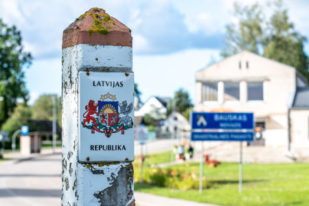 Weathered Latvian border post marked with the national coat of arms and the inscription LATVIJAS...