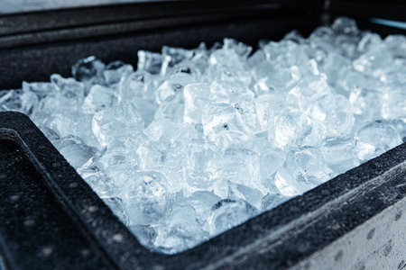 A close-up view of a container filled with clear ice cubes, showing their frozen texture and cold...