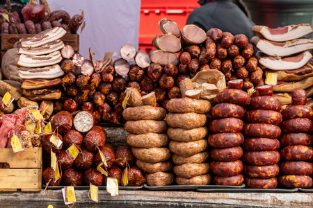 Variety of cured and smoked sausages, salami, and meat cuts displayed at a traditional market stallの写真素材
