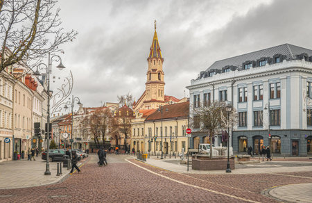 Vilnius, Lithuania - November 22 2025: Rotuse square, Vilnius Old Town, with people walking, Saint Nicolas church, old buildings and trees in autumnのeditorial素材