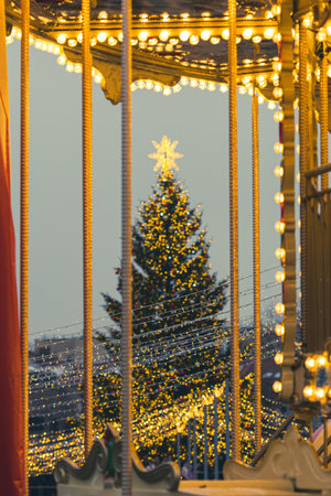 A brightly lit Christmas tree in a festive city square in Vilnius, Lithuania, Europe, surrounded by people, holiday lights and market stallsの写真素材
