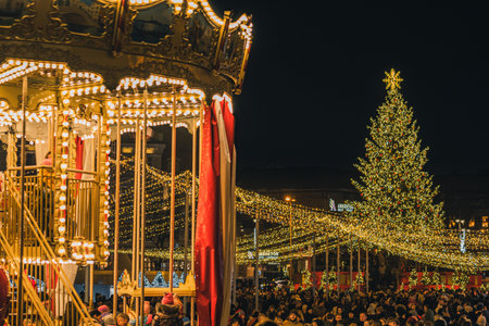 Vilnius, Lithuania - November 30 2025: Beautiful carousel at night in a festive city square in Vilnius, Lithuania, Europe, surrounded by people, holiday lights and market stallsのeditorial素材