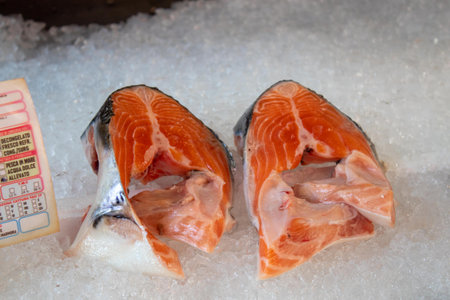 Fresh salmon fillets displayed on crushed ice for sale at a fishmonger's counter