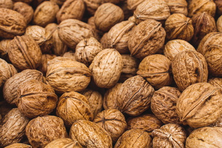 Close-up background of whole walnuts in their shells, showing natural texture, organic food concept,...