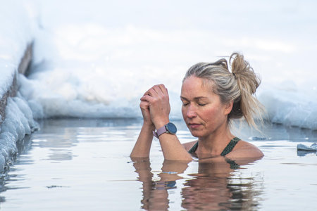Vilnius, Lithuania - January 11 2026: Beautiful blonde hair woman immersed in the freezing cold water of a lake practicing cold water swimming. Wim Hof Method, cold therapy, breathのeditorial素材
