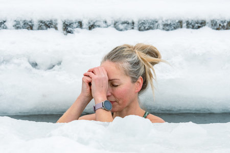 Vilnius, Lithuania - February 8 2026: Beautiful blonde hair woman immersed in the freezing cold water of a lake practicing cold water swimming. Wim Hof Method, cold therapy, breathのeditorial素材