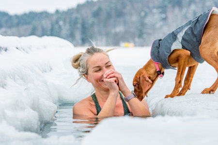 Vilnius, Lithuania - February 8 2026: Beautiful blonde hair woman immersed in the freezing cold water of a lake practicing cold water swimming. Wim Hof Method, cold therapy, breathのeditorial素材