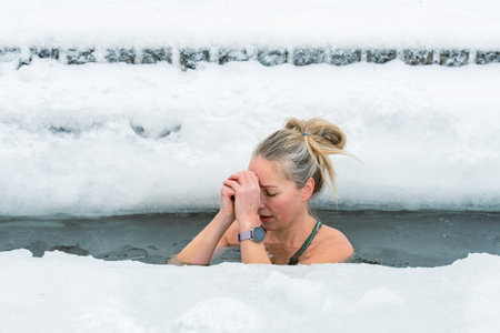 Vilnius, Lithuania - February 8 2026: Beautiful blonde hair woman immersed in the freezing cold water of a lake practicing cold water swimming. Wim Hof Method, cold therapy, breathのeditorial素材