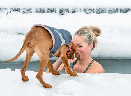 Vilnius, Lithuania - February 8 2026: Beautiful blonde hair woman immersed in the freezing cold water of a lake practicing cold water swimming. Wim Hof Method, cold therapy, breathのeditorial素材